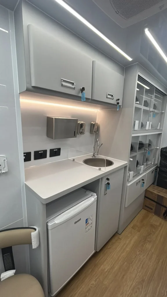 Bancada com pia inox, dispensers de higienização, frigobar e armários com chave na farmácia móvel de Pouso Alegre